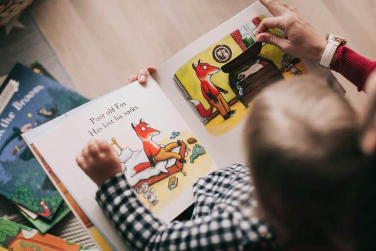 Child reading a picture book about a fox with an adult, showing bright illustrations of the fox's story.