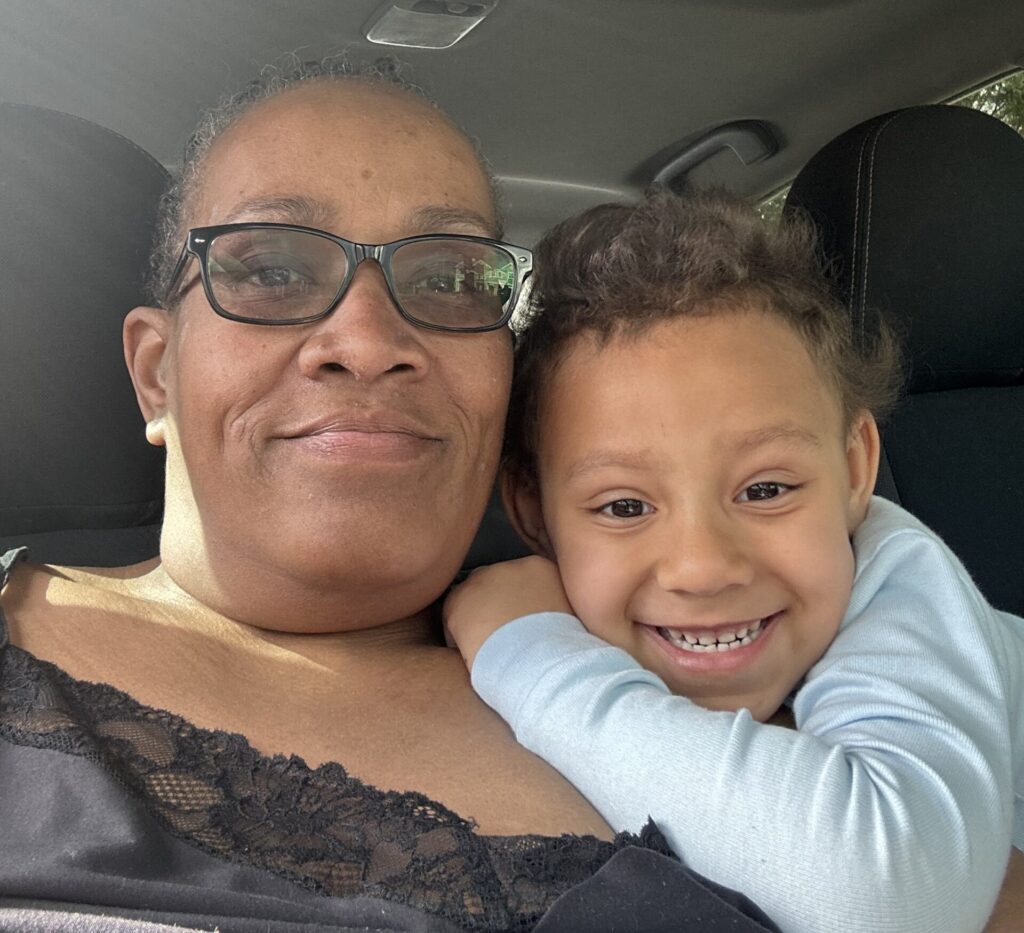 A woman and a smiling child pose together in a car, the child hugging her closely.