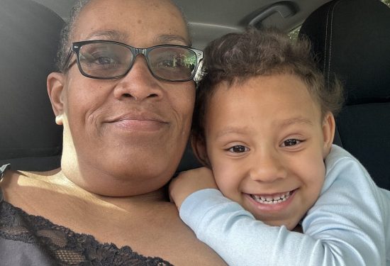 A woman and a smiling child pose together in a car, the child hugging her closely.